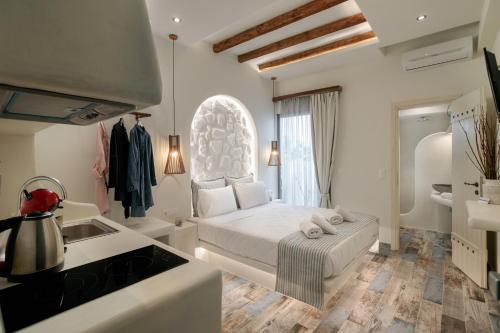 a white bedroom with a bed and a sink at Naxos Petite Studios in Agios Prokopios