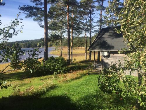 a small house in the grass next to a lake at Strandstuga in Tämta