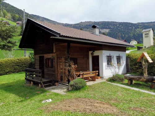 a small wooden cabin with a porch and benches at Waldheimat in Fresach