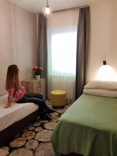 a young girl sitting on a bed in a bedroom at Erdővarázs Panzió in Lillafüred