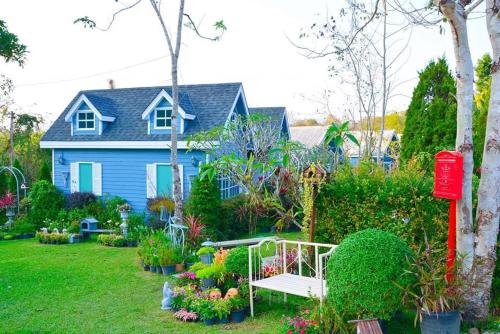 a blue house with a bench in the yard at Baan JaoKorKluay บ้านเจ้ากอกล้วย in Chiang Rai