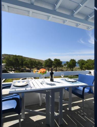 a table and chairs on a balcony with a view of the ocean at Nostos Beachfront Apartments & Studios in Agios Ioannis Tinos