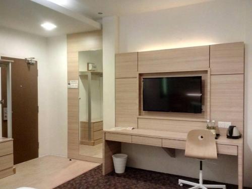 a room with a television and a desk with a chair at The Inn in Bintulu