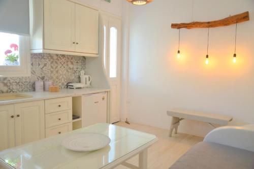 a kitchen with white cabinets and a white table at Veletas Apartments in Adamantas