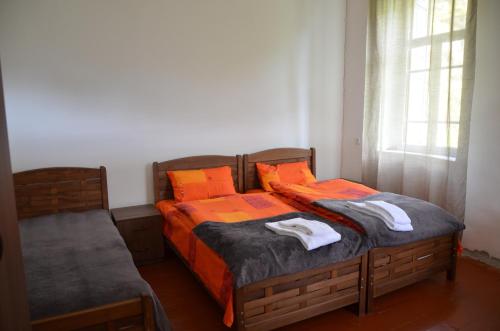 two beds in a bedroom with orange sheets and towels at Vichnashi in Mestia