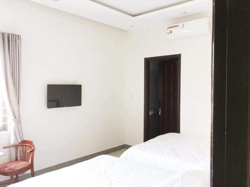 a bedroom with two beds and a tv on the wall at Motel Thanh Long in Da Nang