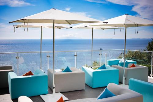 a patio with chairs and umbrellas and the ocean at Villa Fiorella Art Hotel in Massa Lubrense