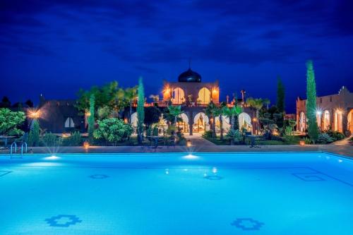 a large swimming pool in front of a house at night at Taj Atlas Wellness Boutique Hôtel & Spa in Amizmiz