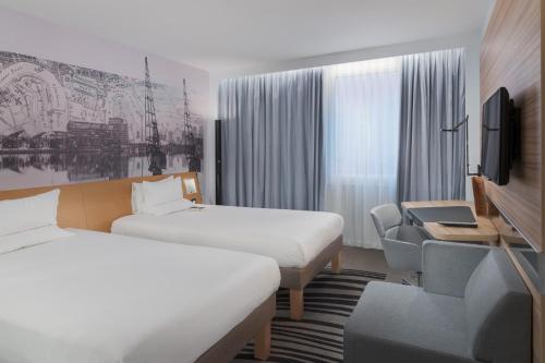 a hotel room with two beds and a tv at Novotel London Excel in London