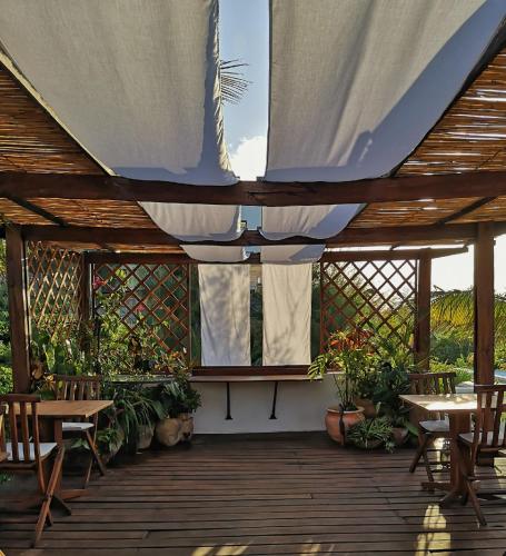 a wooden deck with tables and chairs and a tent at Baia Sonambula in Praia do Tofo