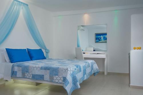a bedroom with a bed with blue sheets and a mirror at Alexandros Village in Adamas