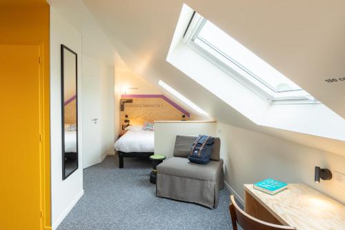 a bedroom with a bed and a chair and a window at greet Hotel Beaune in Beaune
