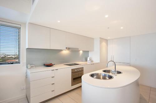 Una cocina con gabinetes blancos y un fregadero. en Blue C Coolangatta, en Gold Coast