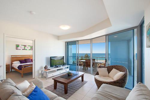 a living room with a couch and a television and a dining room at Blue C Coolangatta in Gold Coast