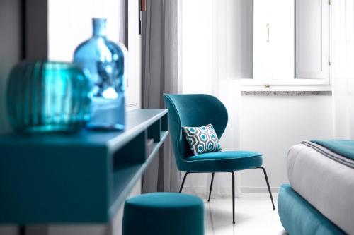 a living room with a chair and a bottle on a desk at Hotel Plaza e de Russie - Relais & Châteaux in Viareggio