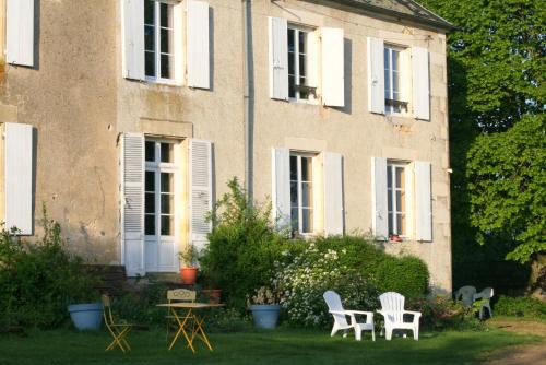 a house with chairs and a table in the yard at Chambres d'hotes du Jay in La Guerche-sur-lʼAubois