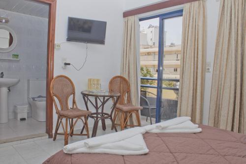 a bedroom with a bed and chairs and a table and a balcony at Danaos Hotel in Chania Town