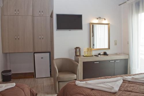 a bedroom with a bed and a chair and a mirror at Danaos Hotel in Chania