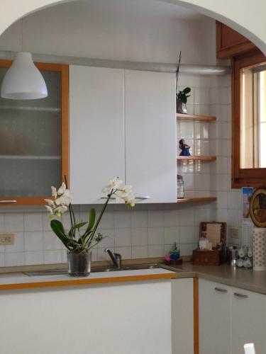 a kitchen with white cabinets and a vase of flowers at A CASA DI GIANCARLA in Bologna