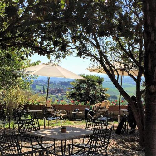 a table and chairs with an umbrella in a garden at Hotel Santa Caterina in Siena