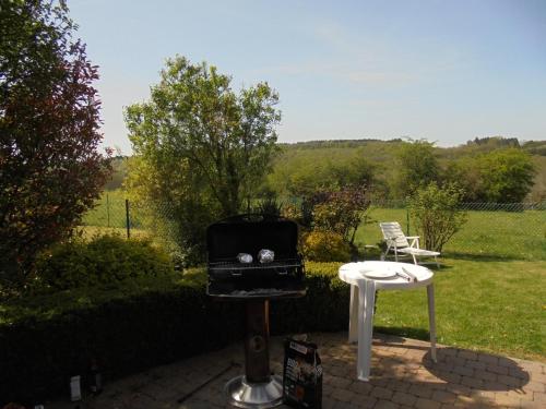 a grill and a table in a yard at Ons huisje "Bienvenidos" met garage in Durbuy