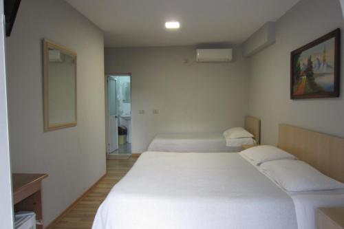 - une chambre avec 2 lits blancs et un miroir dans l'établissement Salku Serviced Rooms, à Tirana