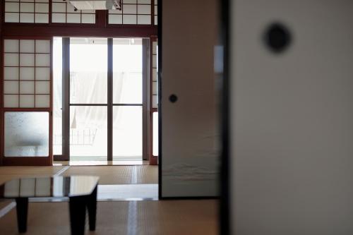 une chambre avec un banc et une porte avec des fenêtres dans l'établissement ゲストハウス たまのや, à Hyuga