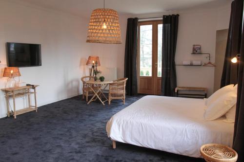 a bedroom with a bed and a table and a window at Eclosion Château Hôtel & Restaurant in Saint-Paul-en-Jarez