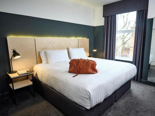 uma mochila sentada numa cama num quarto de hotel em The 1852 Hotel - Self Check-in em Belfast