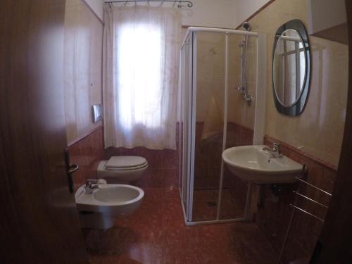 uma casa de banho com 2 lavatórios, um chuveiro e um WC. em Casa Cornaro - Agenzia Cocal em Caorle