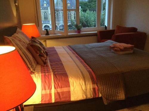 a bedroom with a bed with two lamps and a window at B&B East&West in Ypres