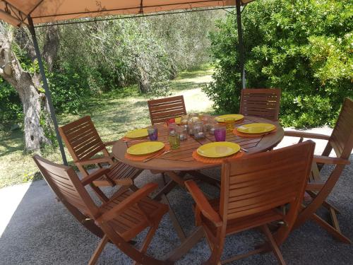 una mesa de madera con sillas y una sombrilla en Il giardino del Salento - Lecce - Casa Vacanze, en Cavallino di Lecce