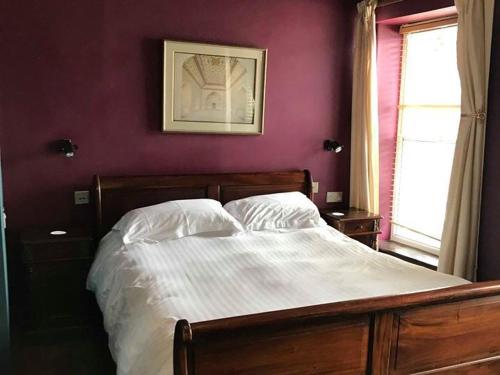 a bed in a bedroom with a purple wall at The Kilverts Inn in Hay-on-Wye