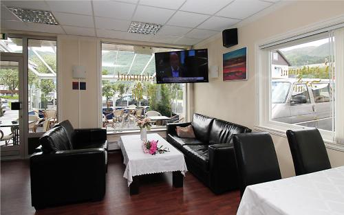 a living room with black leather furniture and a tv at Sentrum Hotel in Nordfjordeid