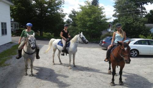 three girls riding on horses in a parking lot at Highland Lake Inn in Andover