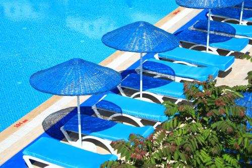 a group of blue chairs with umbrellas next to a swimming pool at Summer Garden Suites Beach Hotel in Bitez