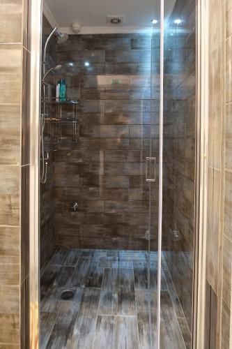 a bathroom with a shower with a wooden wall at Alexis House Studio in Pylos