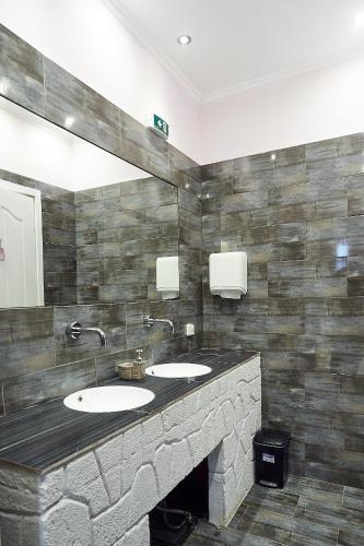 a bathroom with two sinks and a stone wall at Alexis House Studio in Pylos