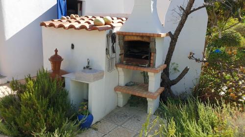 a outdoor kitchen with a pizza oven in a garden at Casas Típicas Algarvias in Arroteia de Baixo