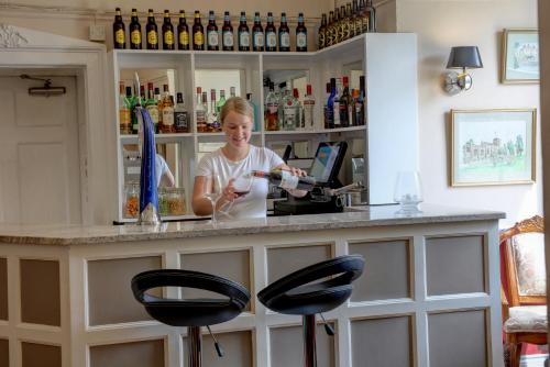 a woman behind a bar with two stools at Best Western Henbury Lodge Hotel in Bristol