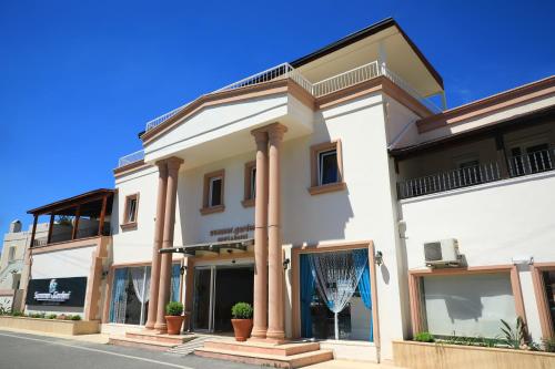 a white building with columns on a street at Summer Garden Suites Beach Hotel in Bitez