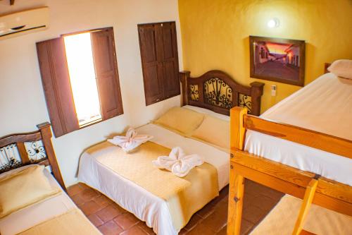 a bedroom with two beds and a window at Casa Hotel Guaracú in Santa Fe de Antioquia