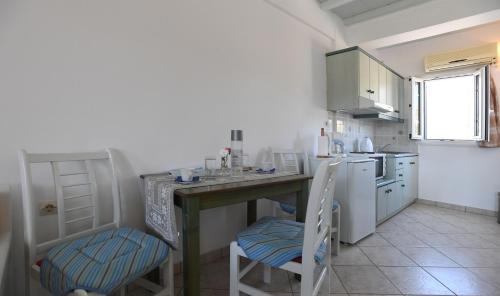 a kitchen with a counter with two chairs and a sink at Nostos Beachfront Apartments & Studios in Agios Ioannis Tinos