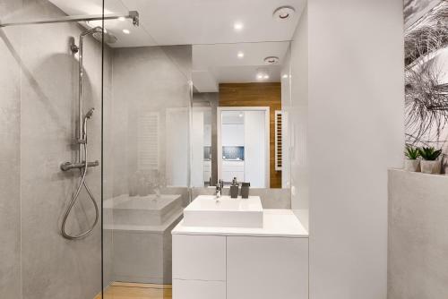biała łazienka z umywalką i prysznicem w obiekcie Blue Mare Bliżej Morza w Kołobrzegu