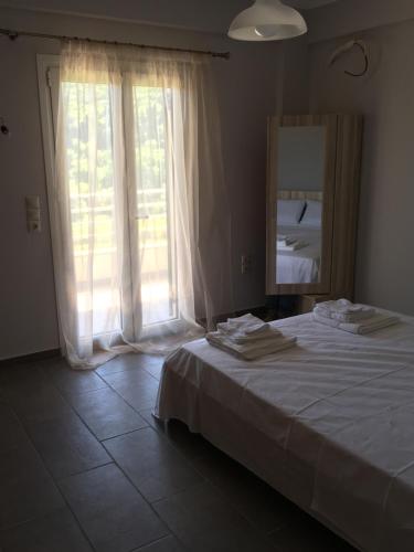 a bedroom with a white bed and a large window at Tsoutsis Apartments in Marantochori