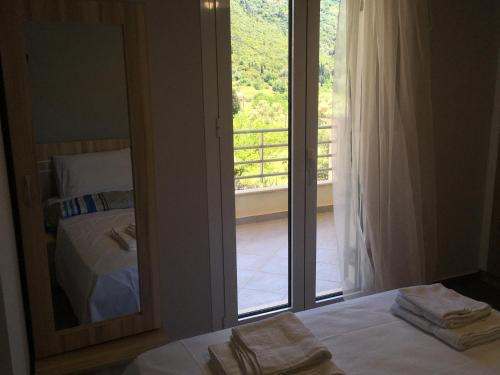 a bedroom with a mirror and a bed and a balcony at Tsoutsis Apartments in Marantochori