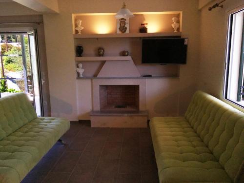a living room with two green couches and a fireplace at Tsoutsis Apartments in Marantochori