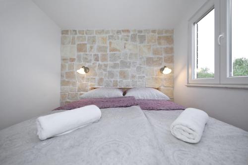 two beds with white pillows in a room with a stone wall at Holiday Home Petar in Drage