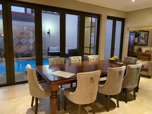 a dining room with a wooden table and chairs at Swanepoel Guesthouse in Jeffreys Bay