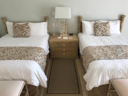 a bedroom with two beds and a nightstand with a lamp at Grand Isla Navidad Golf & Spa Resort with Marina in Barra de Navidad